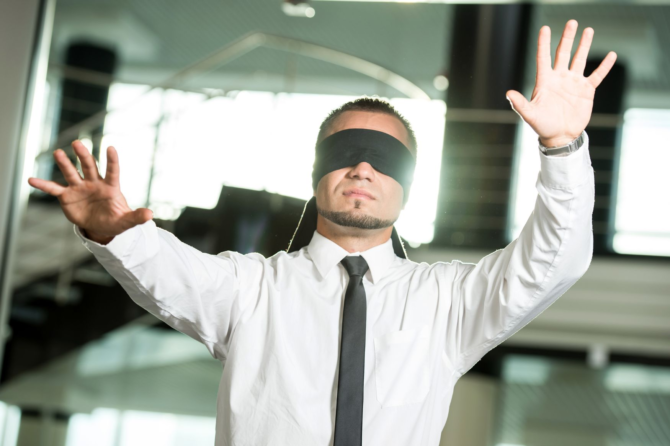 What We Don’t See: Uncovering Hidden Leadership Patterns A businessman in a white shirt and tie lifting a black blindfold to see clearly, symbolizing a leader uncovering hidden leadership patterns.